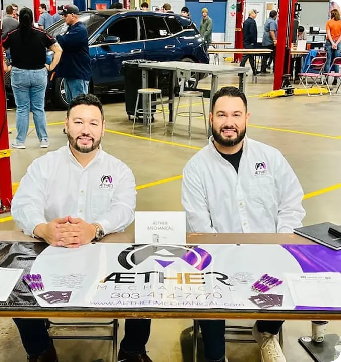 Cornejo Brother wearing white shirts, seated and displaying the Aether logo on a table